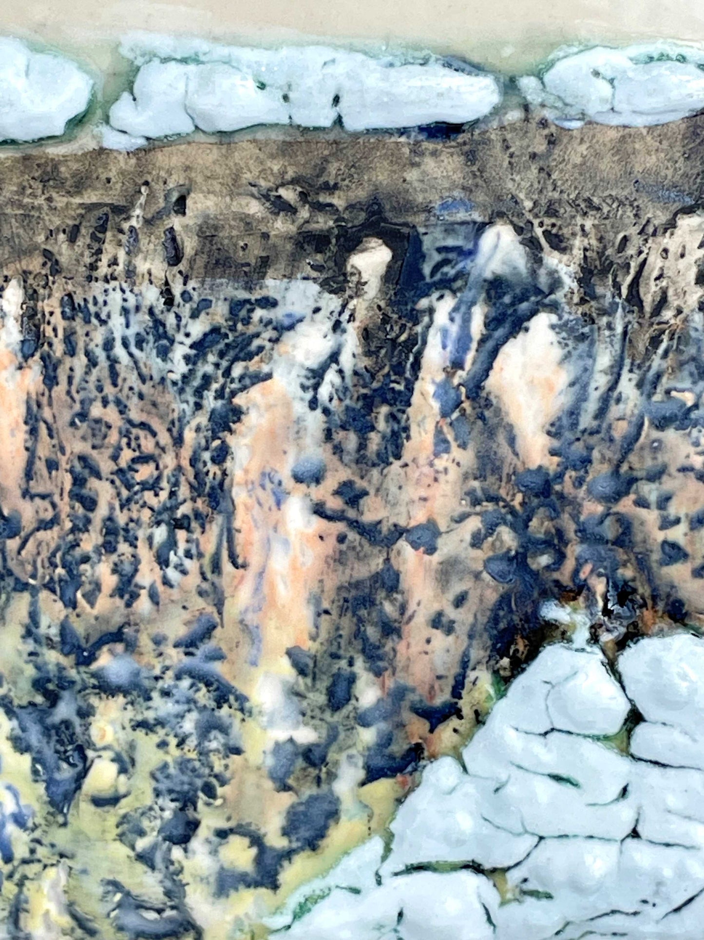 detail of a textured glazed surface of a sculptural tile, with white, grey and coral colors