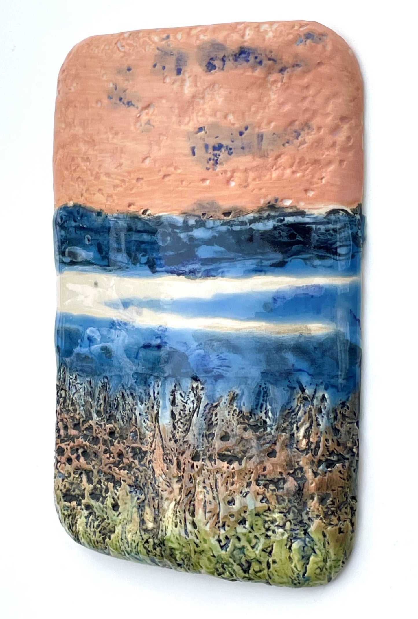 side view of a vertical rectangular porcelain wall-hung decorative tile with coral, blue, white and green glazes and a textured surface, representing an abstract river scene
