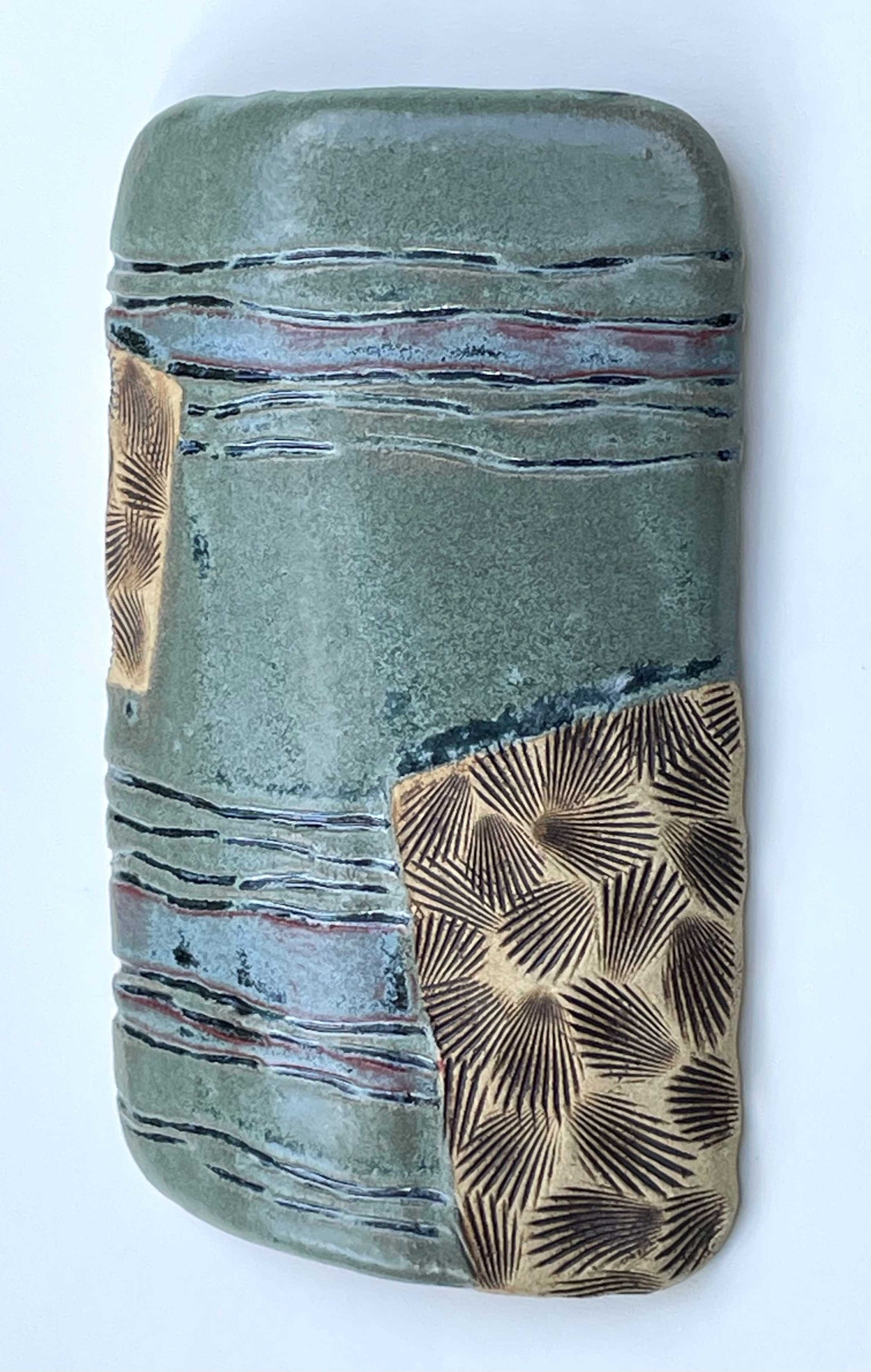 Ceramic tile with textured surface and shell patterns with green, blue and tan color glazes