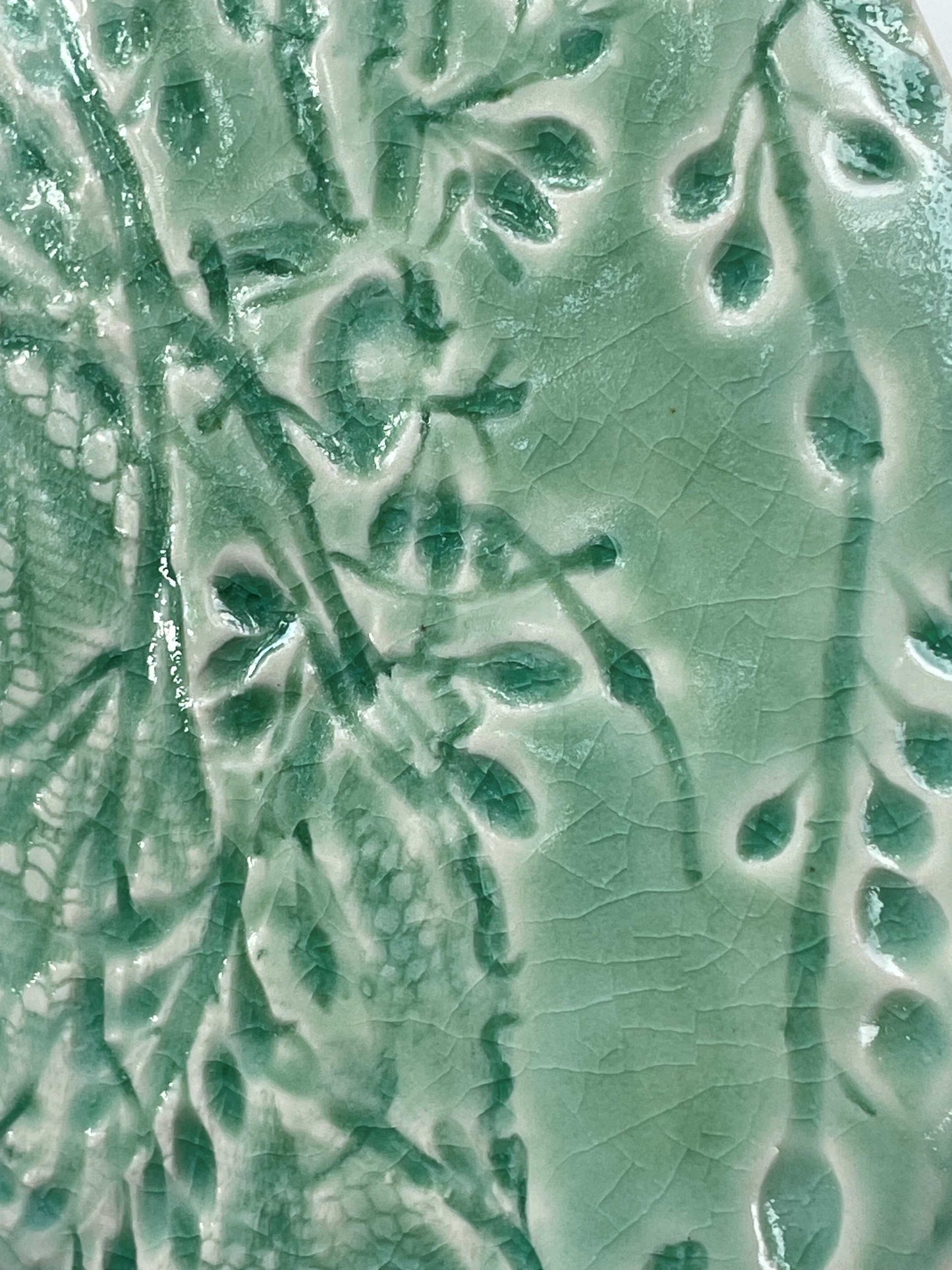 Close-up of a light green ceramic tile with seaweed patterns