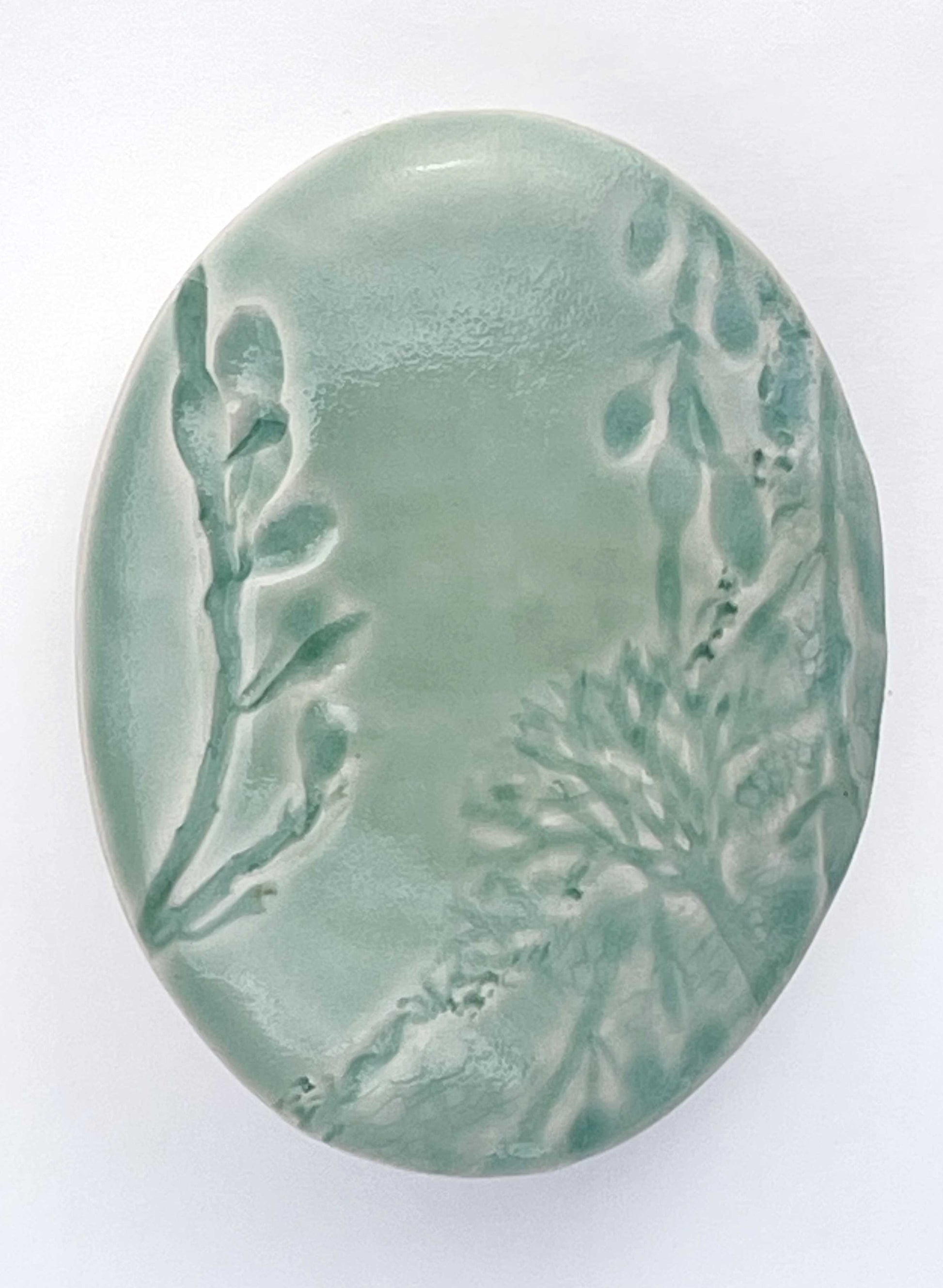 light green oval porcelain wall-hung sculpture with seaweed texture