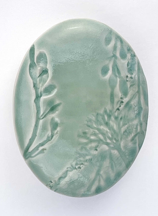 light green oval porcelain wall-hung sculpture with seaweed texture