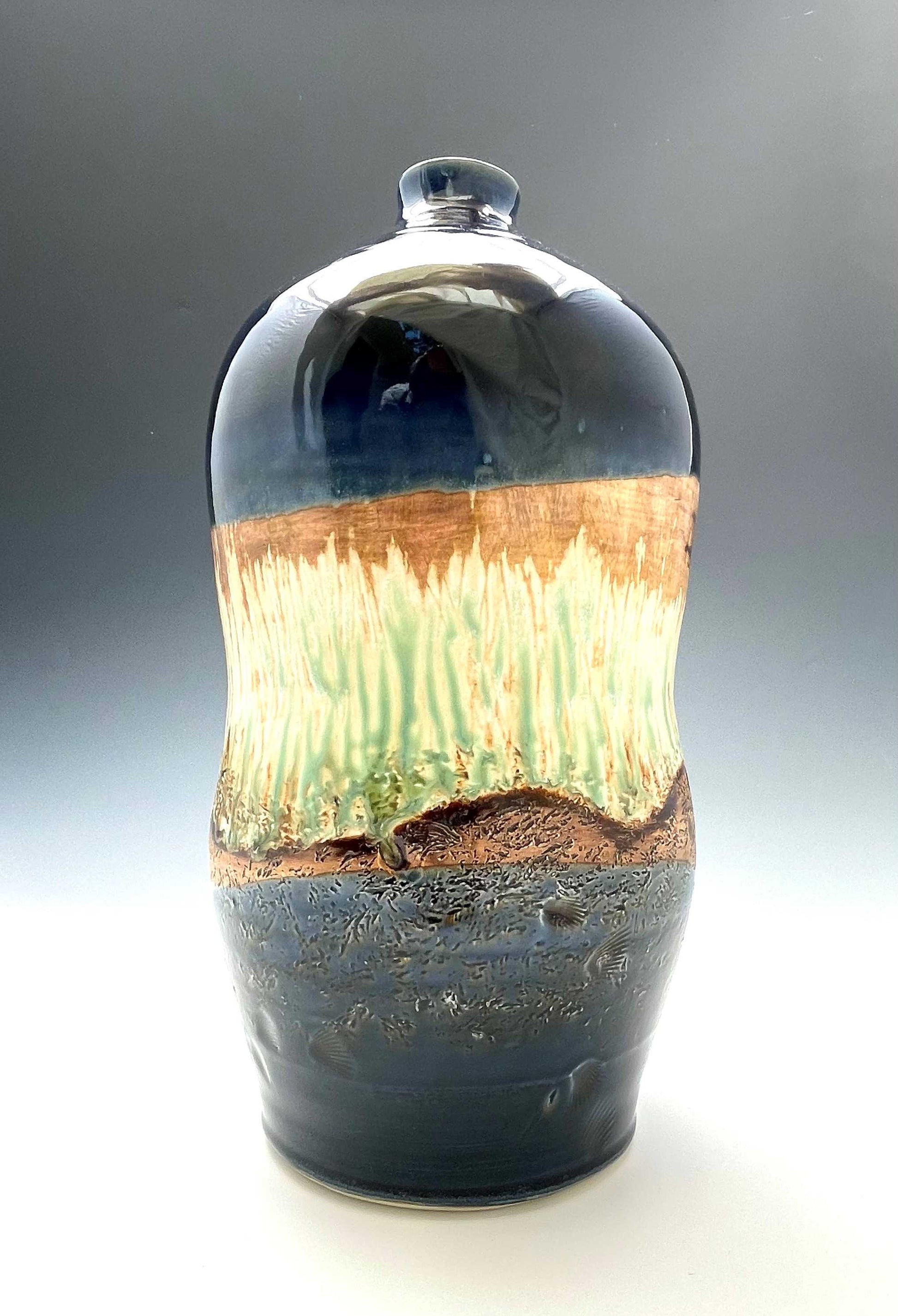 tall porcelain wheel-thrown sculptural vase with dark blue, brown and light green glazes representing a river's edge