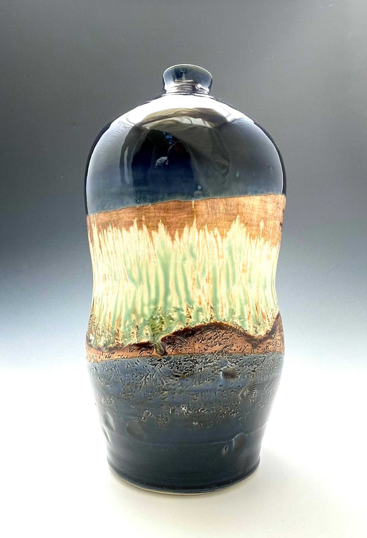 tall porcelain wheel-thrown sculptural vase with dark blue, brown and light green glazes representing a river's edge