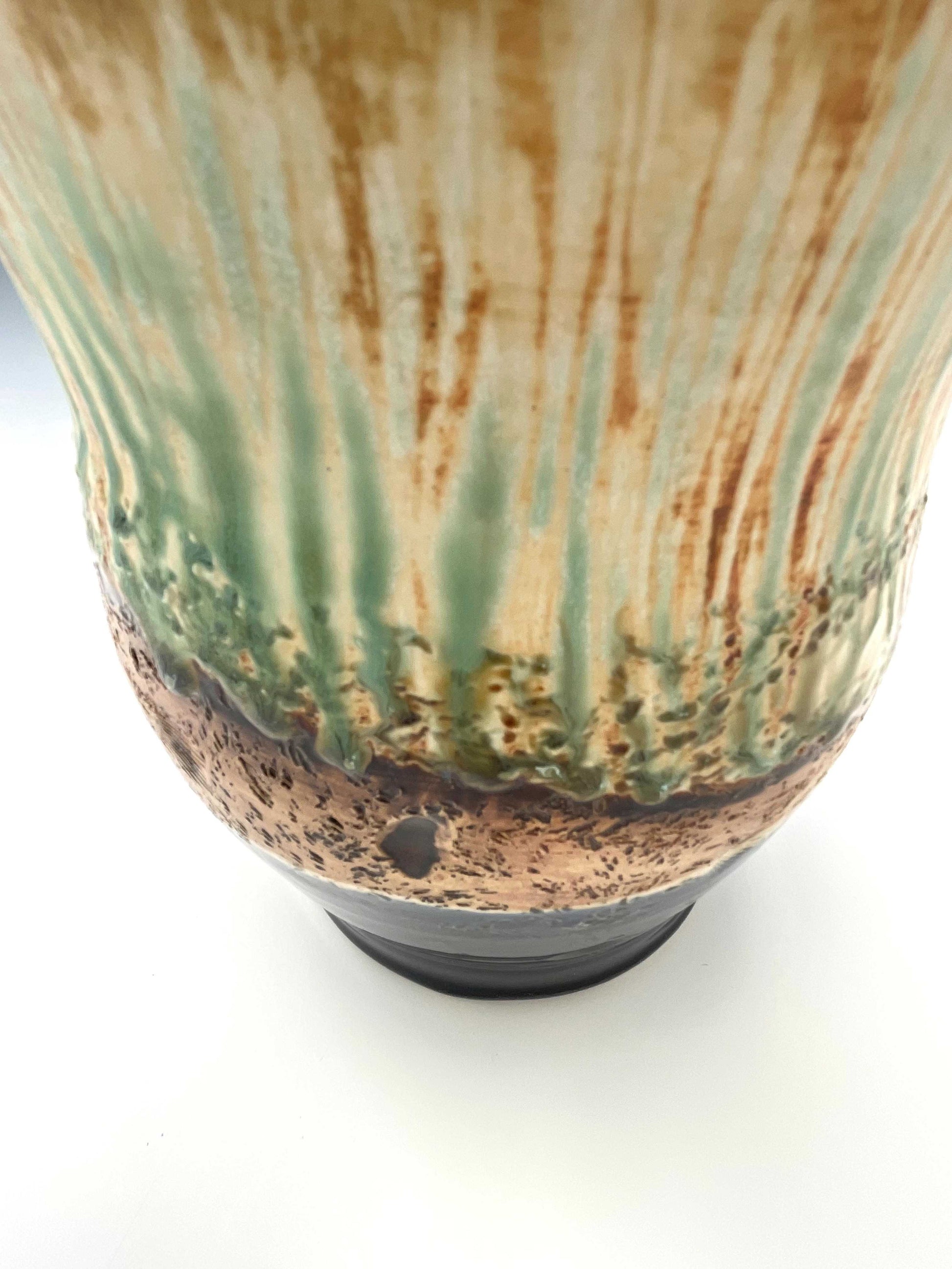 detail of surface of tall porcelain wheel-thrown sculptural vase with dark blue, brown and light green glazes representing river grasses