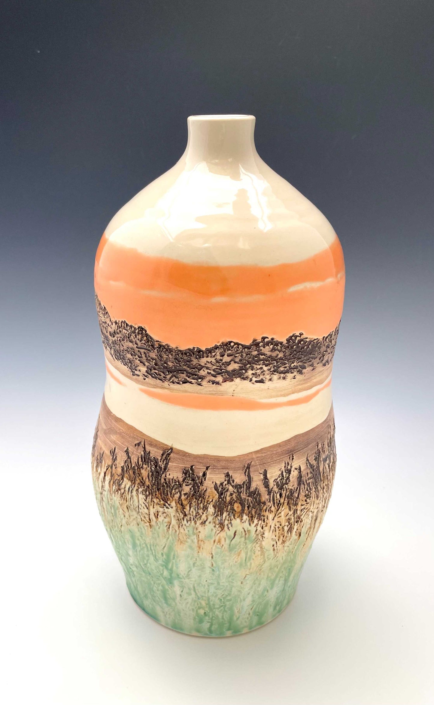 Tall wheel-thrown porcelain vase with coral, brown, white and light green glazes and a textured surface, representing a river sunset scene