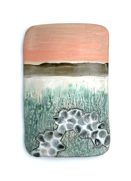Rectangular porcelain wall-hung sculptural tile with coral, white, brown, grey and green glazes on a textured surface, representing an abstract sunset landscape scene by the water