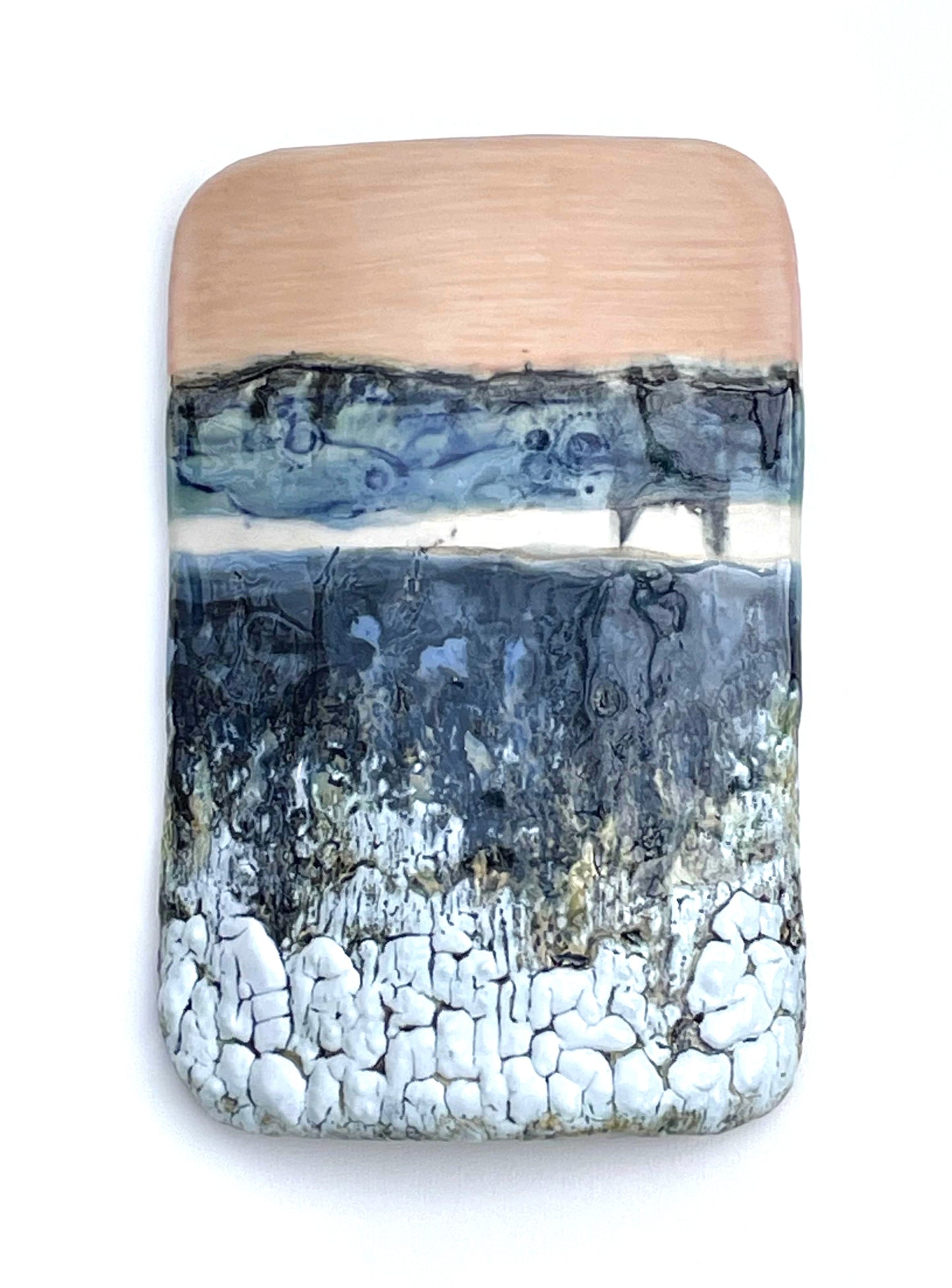 Rectangular porcelain wall-hung sculptural tile with coral, white, blue and dark grey glazes on a textured surface, representing an abstract sunset landscape scene