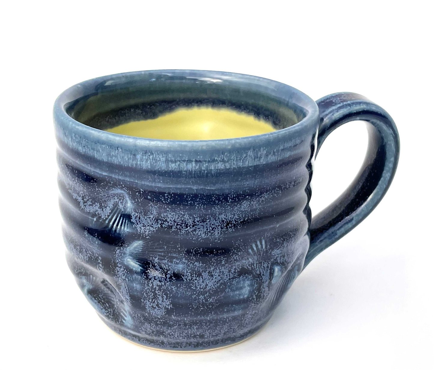 Blue ceramic mug with a textured surface and a yellow glazed interior