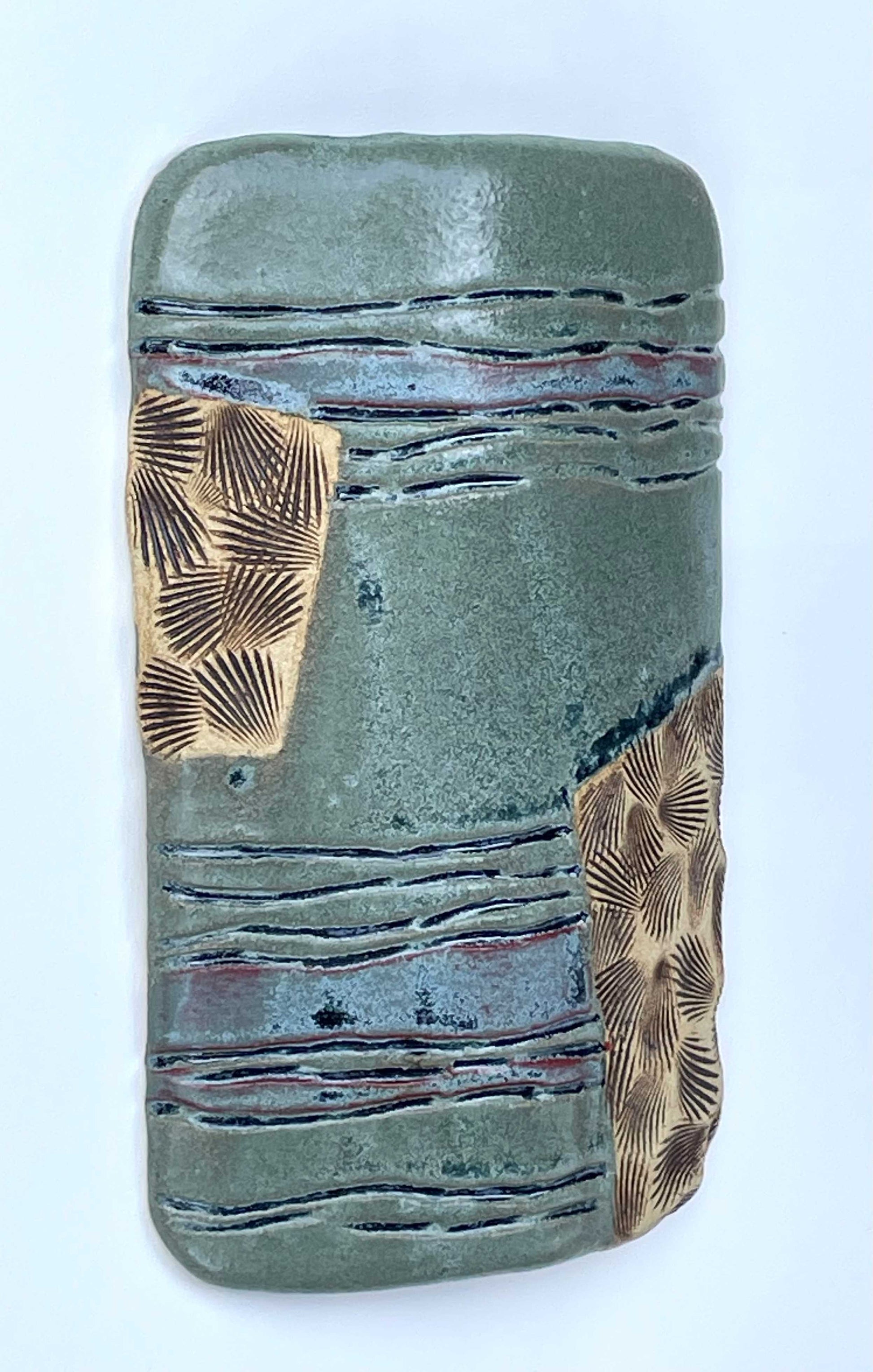 Ceramic tile with textured surface and shell patterns with green, blue and tan color glazes