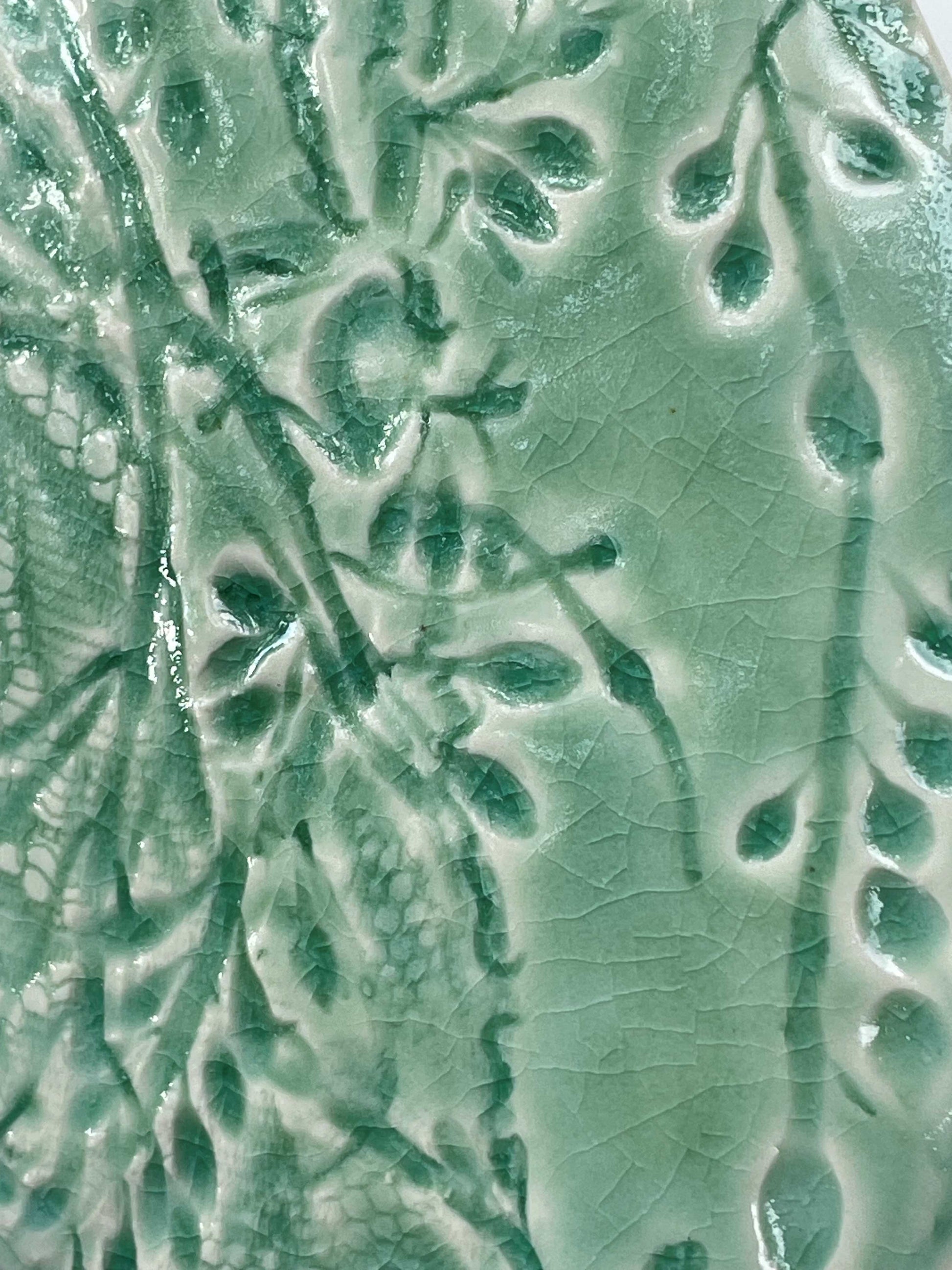 Close-up of a light green ceramic tile with seaweed patterns