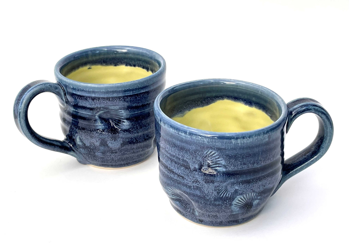 Blue ceramic mug with a textured surface and a yellow glazed interior