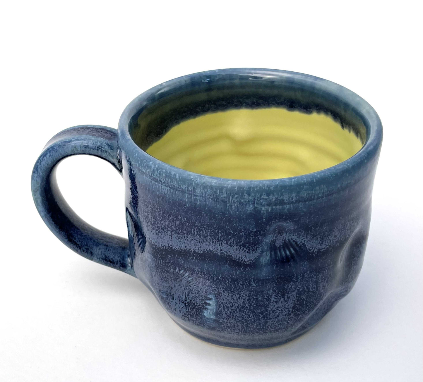 Blue ceramic mug with a textured surface and a yellow glazed interior